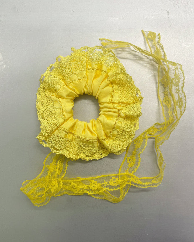 Yellow lace scrunchie with a ribbon on a light gray background