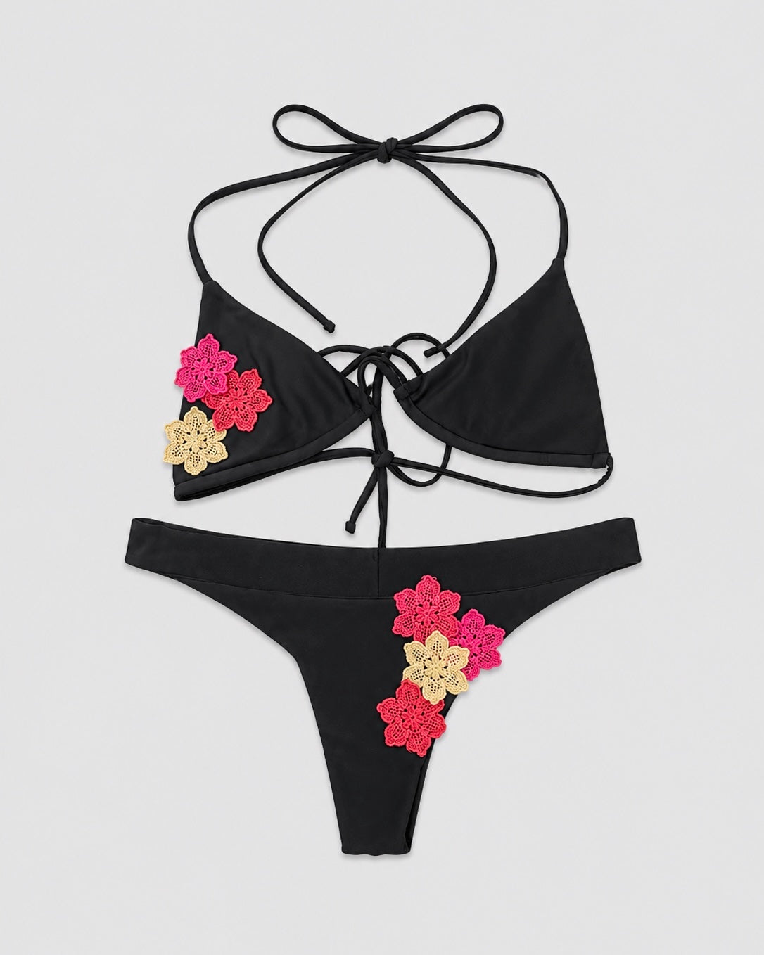 Black bikini set with floral embellishments on a light gray background