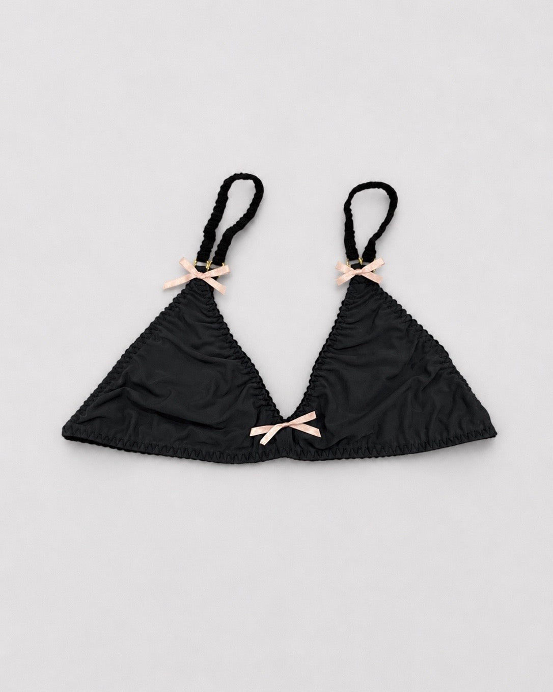 Black bralette top with pink bows on a light gray background