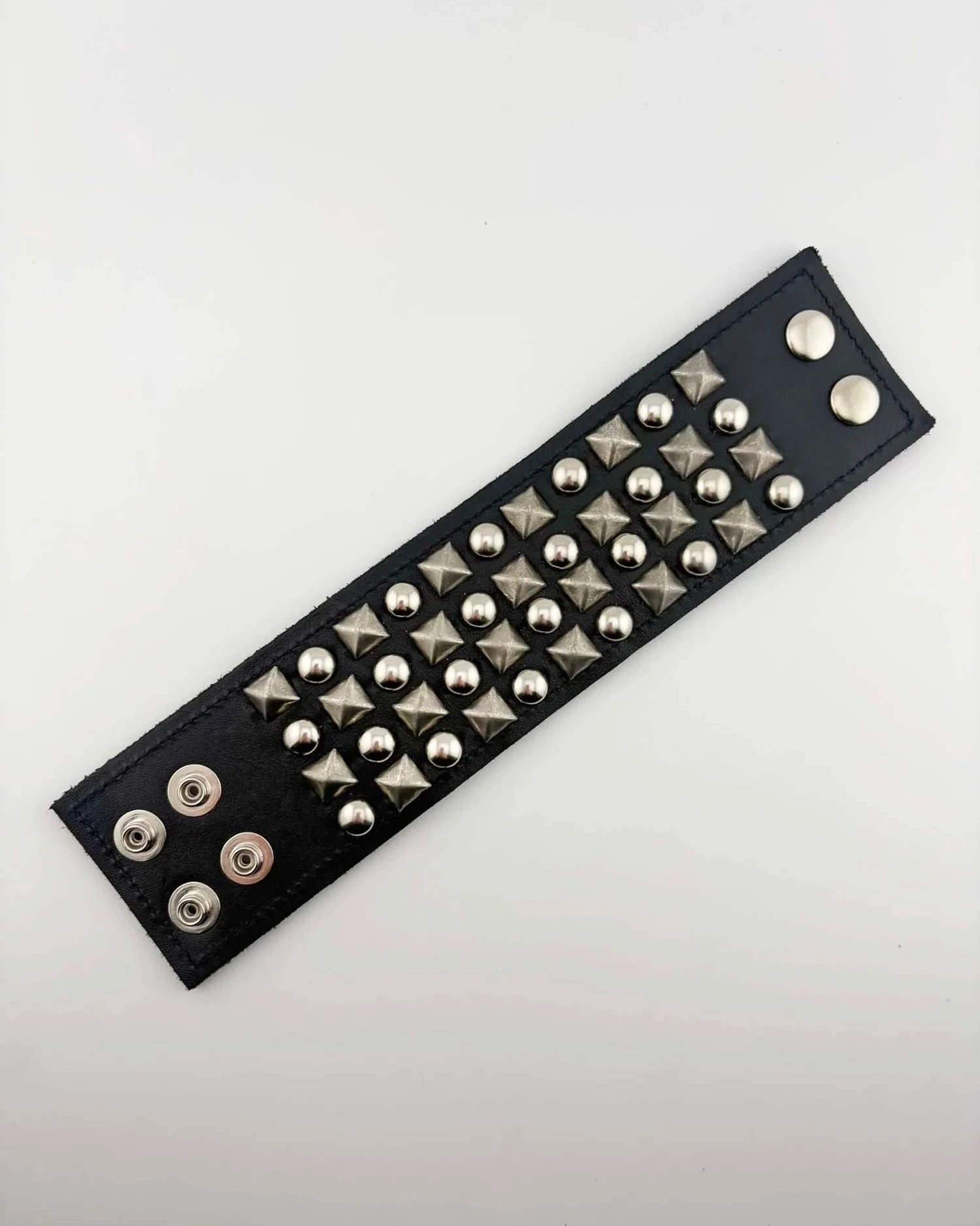 Black leather bracelet with silver studs on a white background