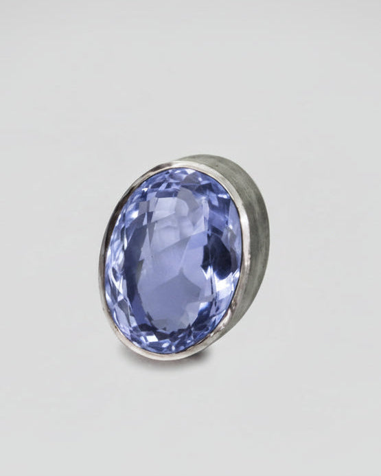 purple gemstone in a silver setting on a gray background