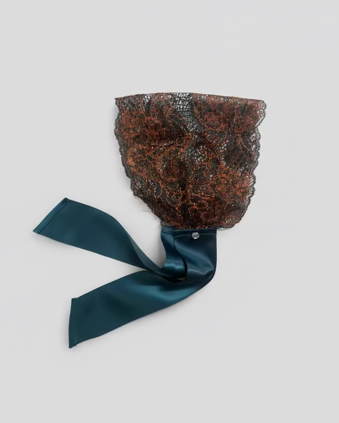 Decorative headband with textured design and teal ribbon on a light gray background