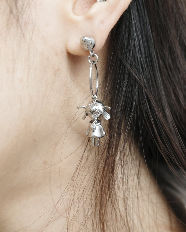 Close-up of a person wearing silver earrings with a neutral background