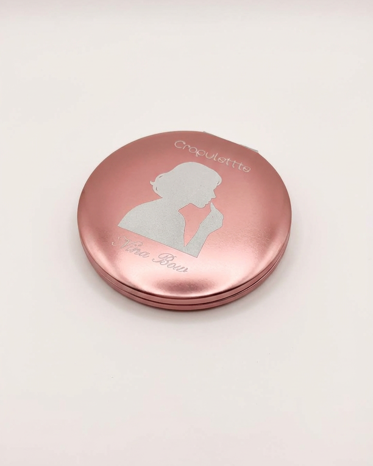 Rose gold compact mirror with a silhouette design on a light pink background