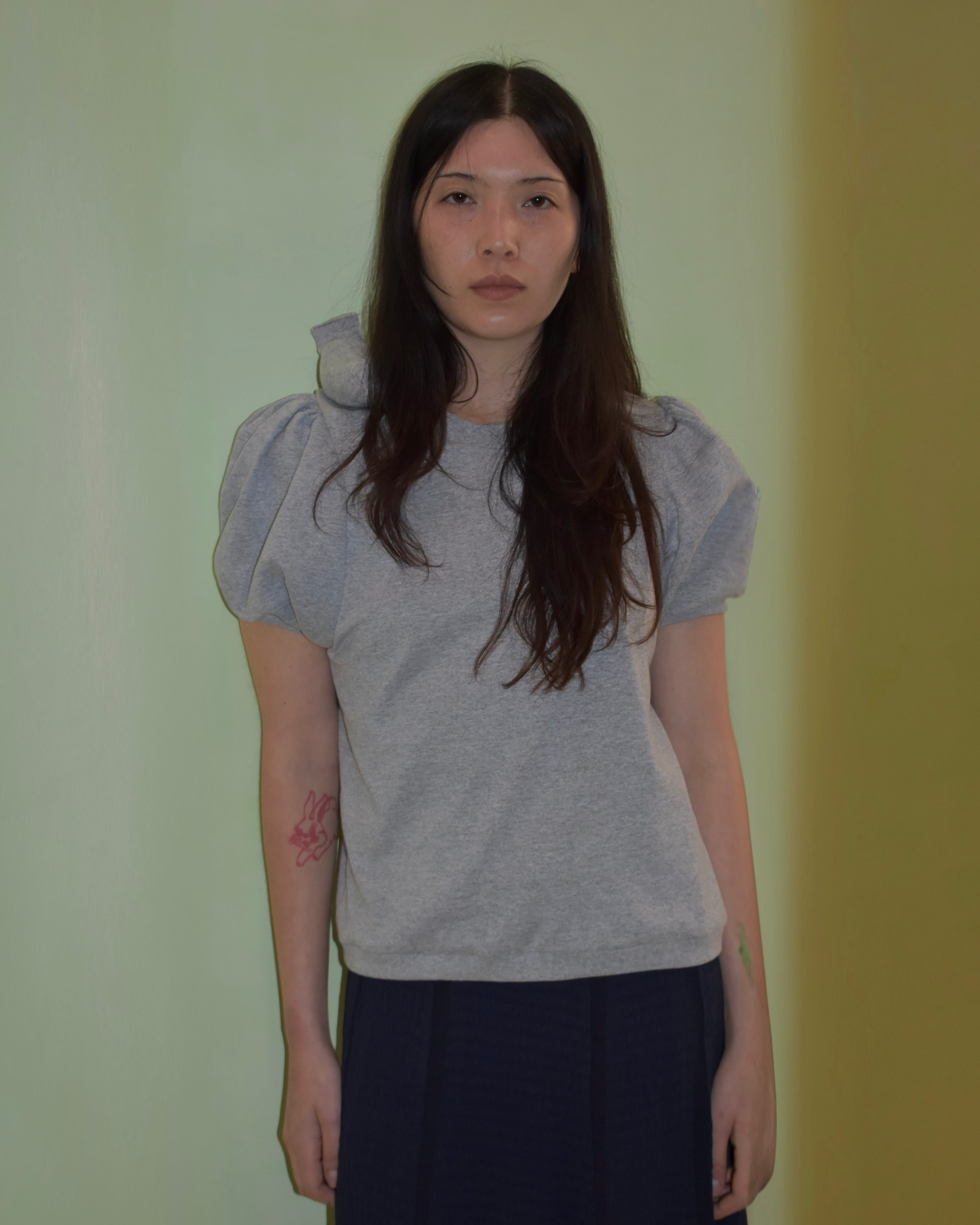 Woman wearing a gray top with puffed sleeves against a plain background