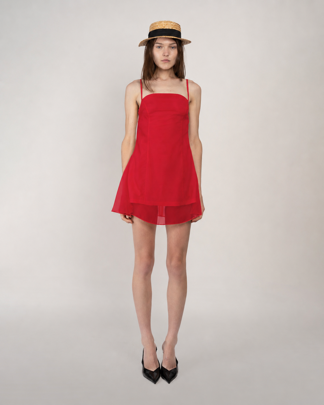 Woman wearing a red dress and straw hat on a plain background